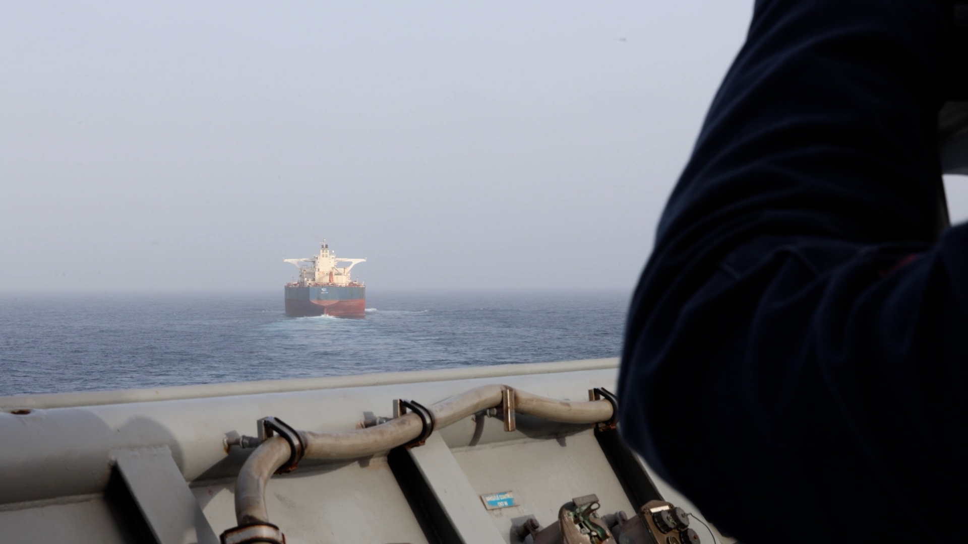 Amerykański marynarz na pokładzie USS Comstock (LSD 45) obserwuje statek handlowy podczas egzekwowania amerykańskiej blokady przeciwko Iranowi
