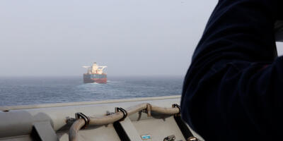 Amerykański marynarz na pokładzie USS Comstock (LSD 45) obserwuje statek handlowy podczas egzekwowania amerykańskiej blokady przeciwko Iranowi