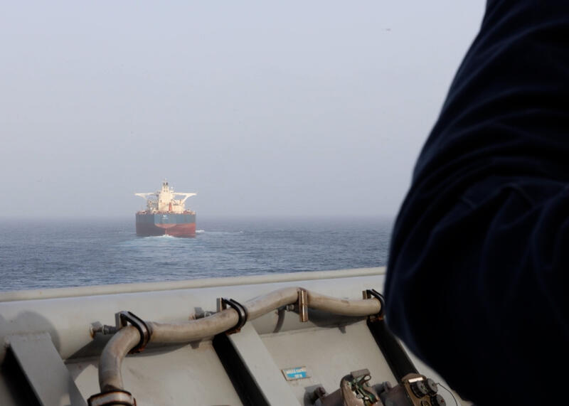 Amerykański marynarz na pokładzie USS Comstock (LSD 45) obserwuje statek handlowy podczas egzekwowania amerykańskiej blokady przeciwko Iranowi